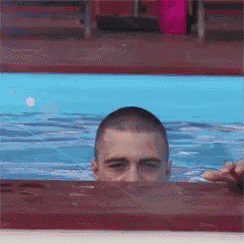 a man is swimming in a pool and looking over the edge