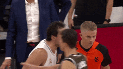 a man in an orange shirt with the letter s on it kisses another man