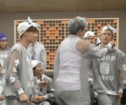 a group of young men are standing in a room and one of them is wearing a sweatshirt that says sgdp