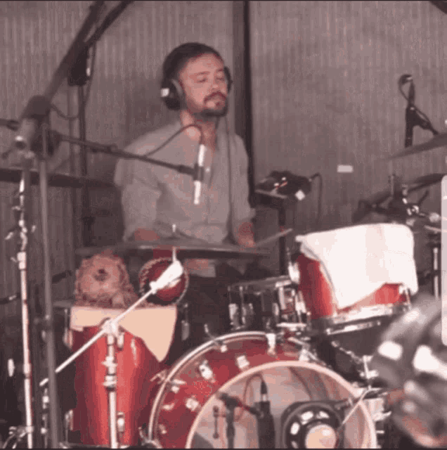 a man wearing headphones is playing drums in a recording studio