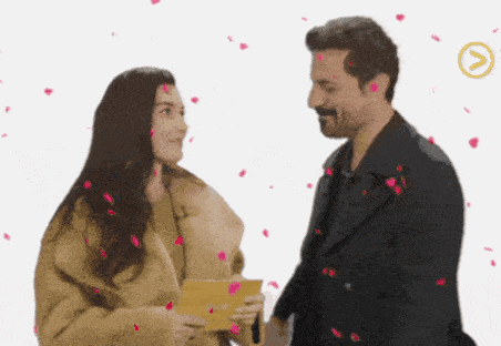 a man and a woman are standing next to each other with petals falling around them