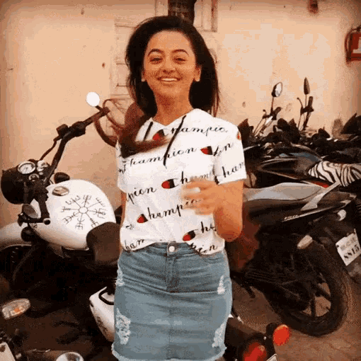 a woman wearing a champion t-shirt stands in front of a motorcycle
