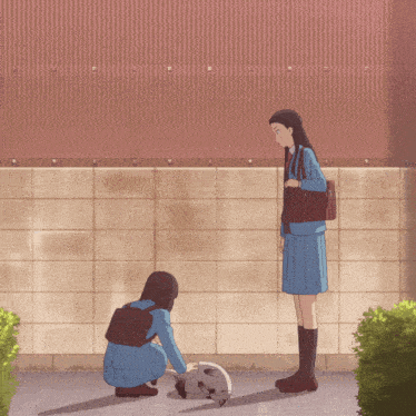 two girls in school uniforms are looking at a cat on the ground