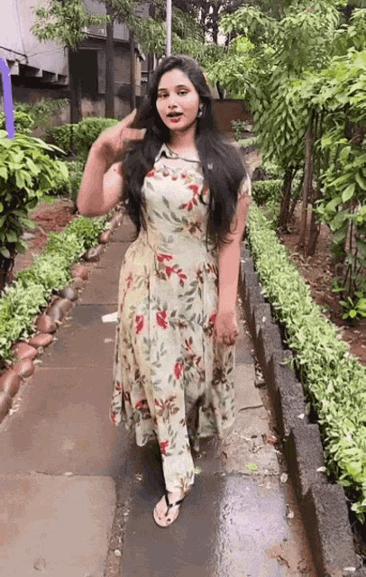 a woman in a floral dress is walking down a sidewalk