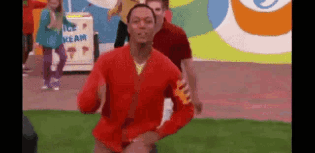 a man in a red jacket is dancing in front of a group of people .