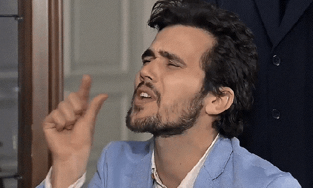 a man with a beard is wearing a light blue jacket and white shirt