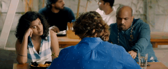 a man in a blue shirt sits at a table with two women