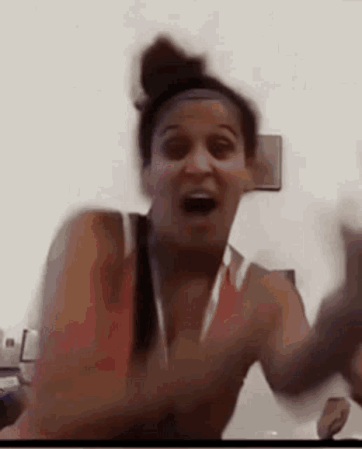 a woman is making a funny face with her hands in the air while wearing a headband .