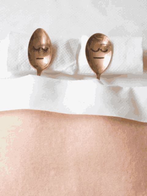two gold spoons with faces on them sit on a napkin