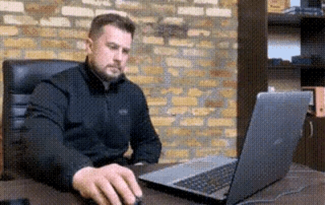 a man is sitting at a desk with a laptop computer .