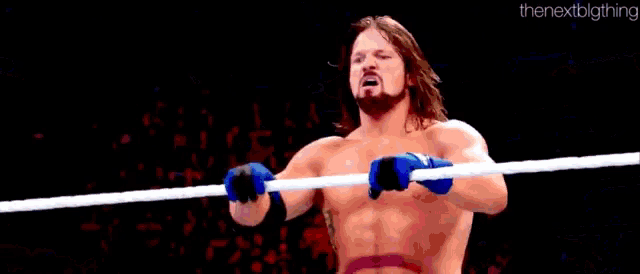 a wrestler is jumping over another wrestler in a ring while a referee looks on .
