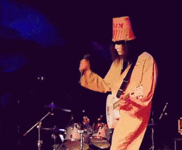 a man in a bucket hat is playing a guitar on stage
