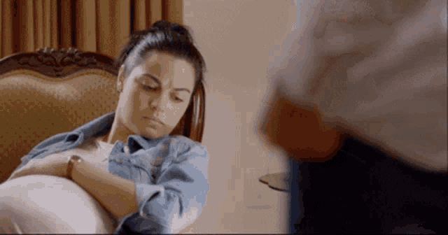 a woman is sitting in a chair with her head resting on her stomach