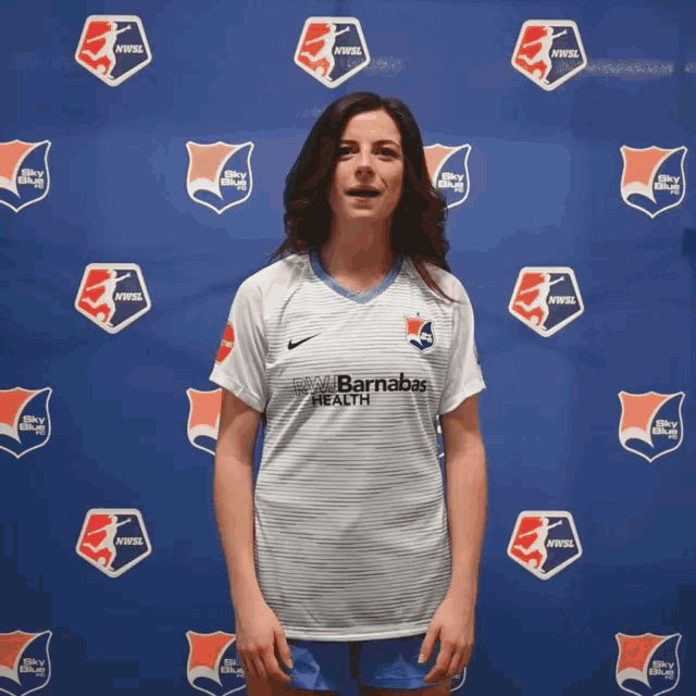 a woman stands in front of a backdrop that says nvfsl