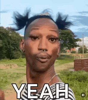 a man with pigtails and a nose ring is standing in a field .