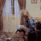 a person is sitting on a couch in a living room with a window .