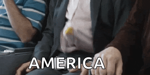 a man in a suit is sitting next to a woman in a striped shirt and the word america is visible