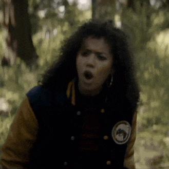 a woman wearing a varsity jacket is making a funny face .