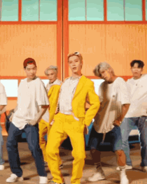 a man in a yellow suit is dancing with a group of men