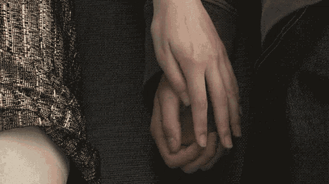 a person holding another person 's hand with a black background