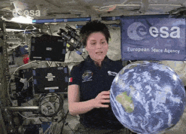a woman holds a globe in front of a european space agency sign