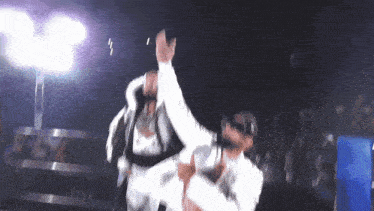 two men are dancing in front of a crowd and one of them is wearing a white shirt that says ' a ' on it