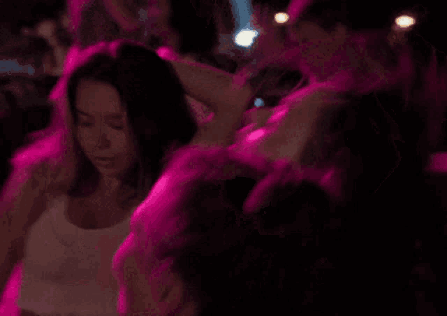 a woman in a white crop top is dancing in a pink light
