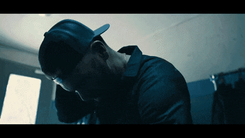 a man wearing a hat and a black jacket is looking down