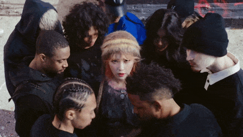 a group of people are gathered around a girl in a black fur coat