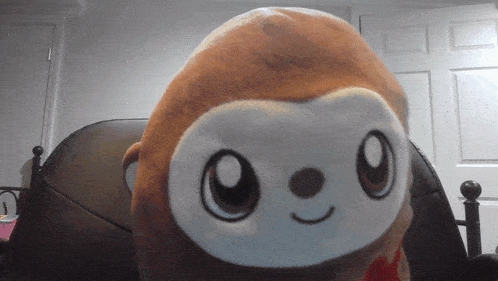 a stuffed monkey is sitting on a bed in front of a white door