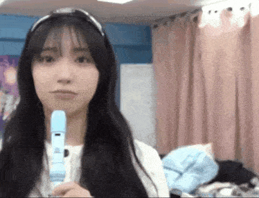 a young woman is holding a blue recorder in her hand .