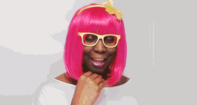 a woman in a pink wig and glasses is smiling