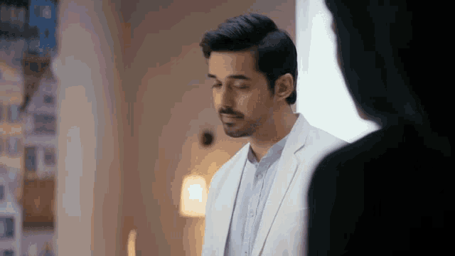 a man in a white suit is standing next to a woman .