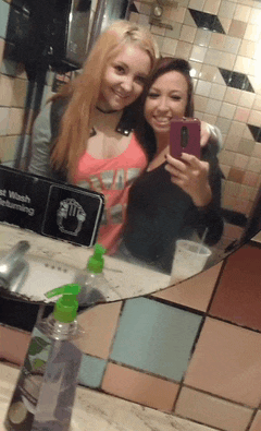 two girls are taking a selfie in front of a sign that says " fast wash returning "