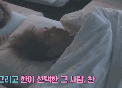 a group of people laying on a bed with korean writing on the blanket