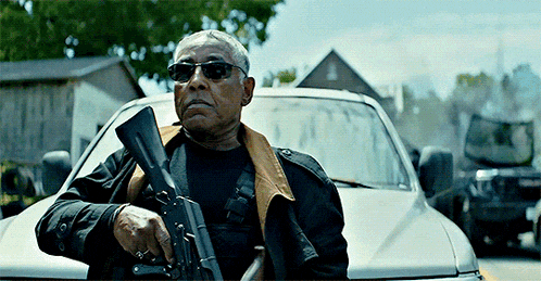 a man holding a gun in front of a silver car