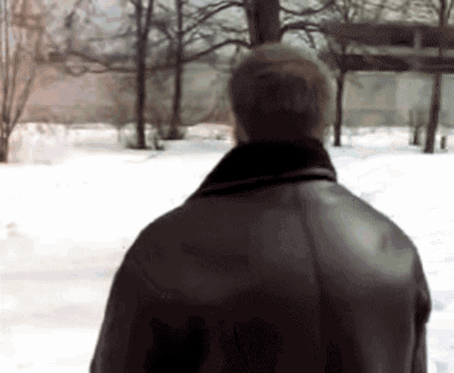 a man in a leather jacket stands in the snow