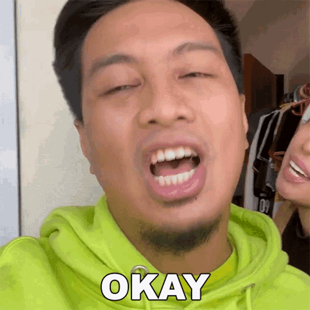 a man in a green hoodie is making a funny face and says okay