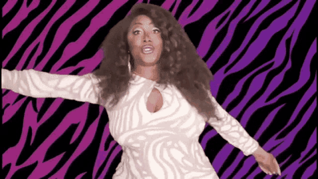 a woman in a zebra print dress is dancing in front of a purple and black zebra print background .