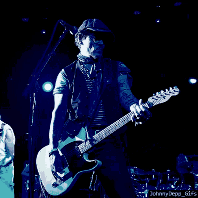 a man is playing a guitar in front of a microphone with a watermark that says johnnydepp_gifs