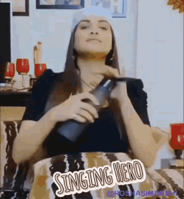 a woman is sitting on a couch singing into a microphone while wearing a santa hat .