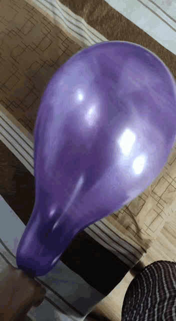 a person is holding a large purple balloon in their hand