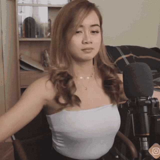 a woman in a white top is sitting in front of a microphone with an o on it