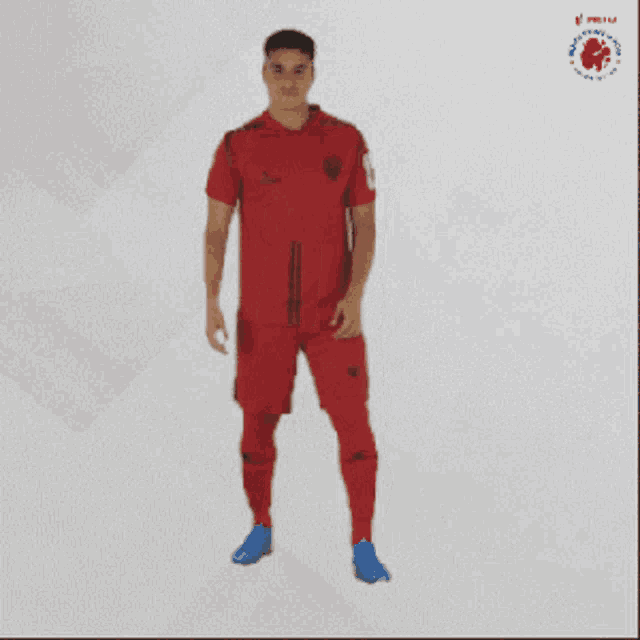 a man wearing a red shirt and shorts is standing with his arms outstretched