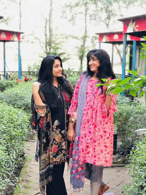 two women are standing next to each other on a path