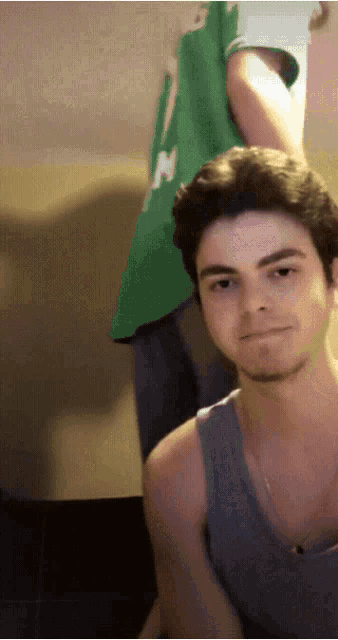 a man wearing a green shirt with the letter n on it looks at the camera