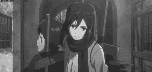 a black and white photo of a girl in a scarf standing in front of a building .