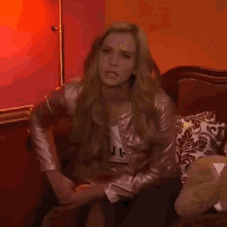a woman in a pink jacket is sitting on a couch in a living room .