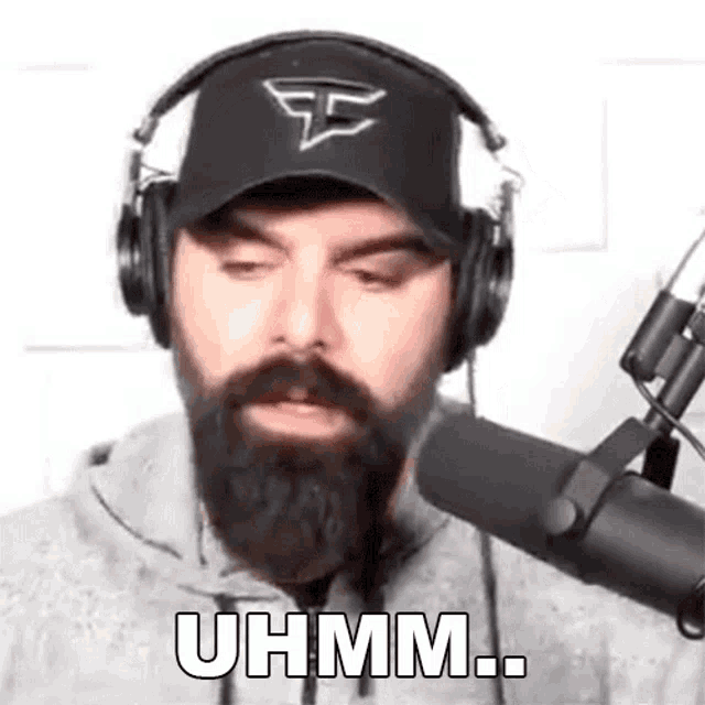 a man with a beard and headphones is standing in front of a microphone .