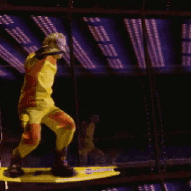 a man in a yellow and orange costume is riding a yellow board